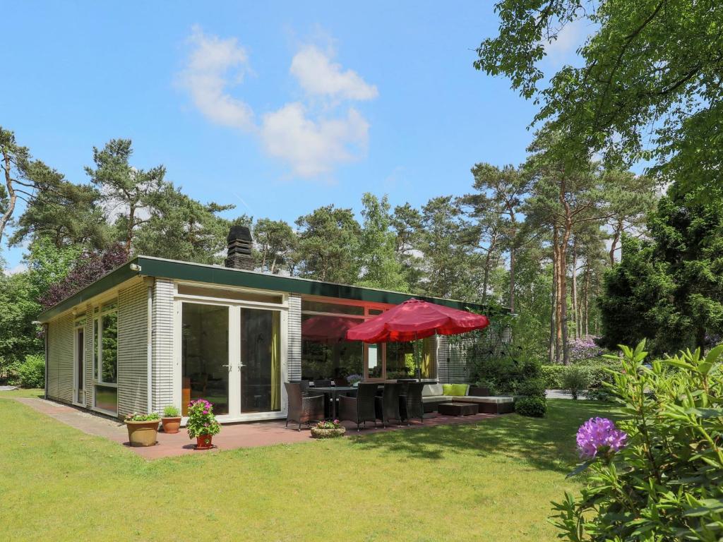 ein kleines Haus mit einem roten Regenschirm im Hof in der Unterkunft Beautiful Holiday Home with Garden in Huijbergen in Huijbergen
