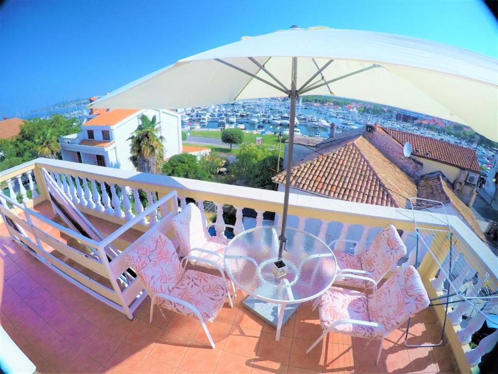 einen Balkon mit einem Tisch, Stühlen und einem Sonnenschirm in der Unterkunft Orange city apartment's Repić in Biograd na Moru