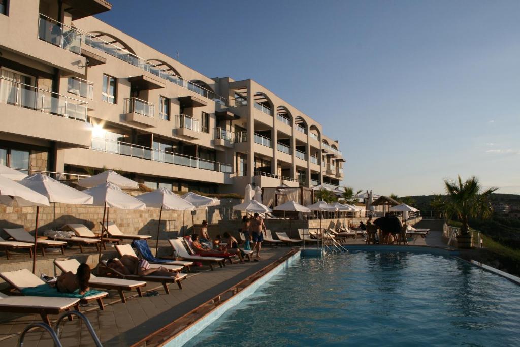 a hotel with a swimming pool with lounge chairs and a hotel at Apartments "Ofir" in Sozopol