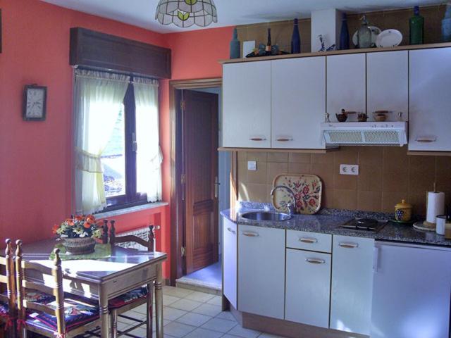 una cucina con armadi bianchi, tavolo e sidro di sidro. di Apartamentos Peña Ubiña a Tuiza de Abajo