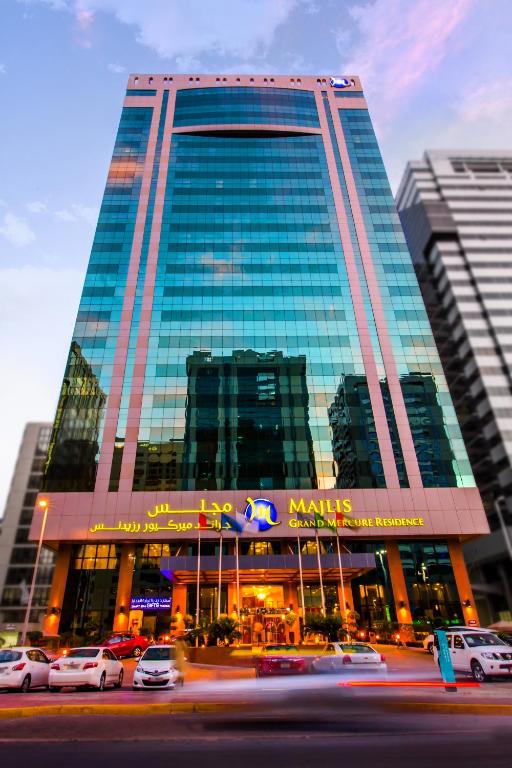 a tall building with cars parked in front of it at Grand Mercure Majlis Residences in Abu Dhabi