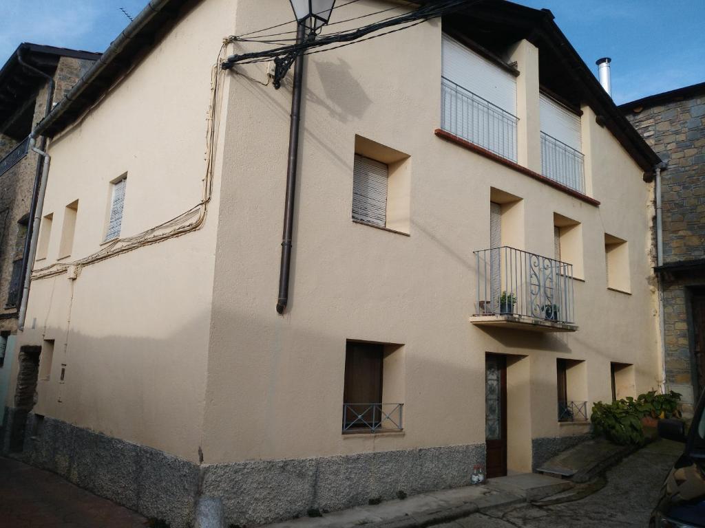 a white building with balconies on a street at Casa Cal Galceran in Alás