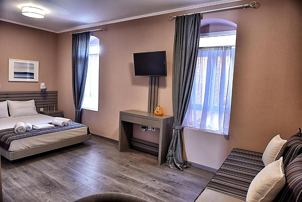 een slaapkamer met een bed en een tv. bij Melina Hotel - Central in Poligiros