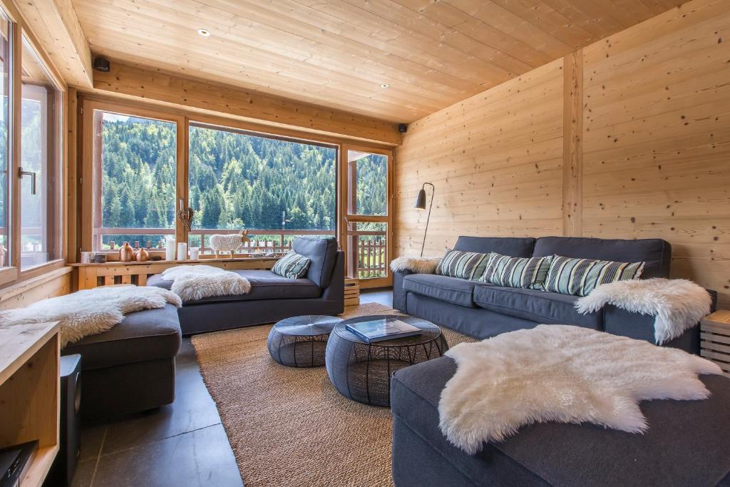 uma sala de estar com sofás e uma grande janela em Appartement Le Danay 10 personnes em Le Grand-Bornand