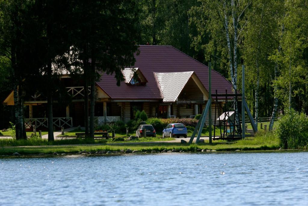 ein Haus mit Autos, die vor einem See geparkt sind in der Unterkunft Jaunsētas in Alūksne