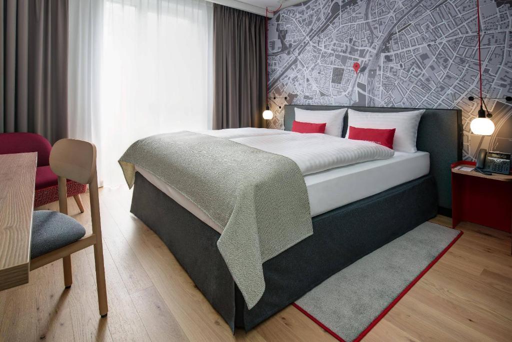 a bedroom with a large bed with red pillows at IntercityHotel Duisburg in Duisburg