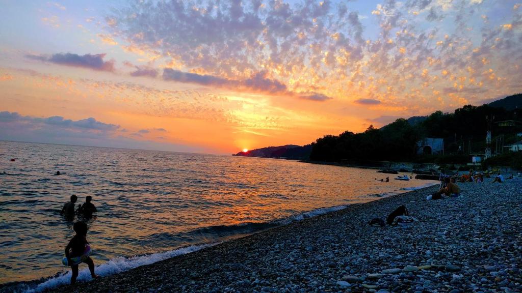 a group of people on a beach at sunset at At Tsyurupy Sochi Apartment in Sochi