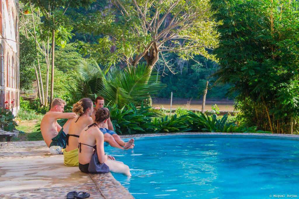 a group of people sitting around a swimming pool at Lobo Hostel - Rurrenabaque in Rurrenabaque