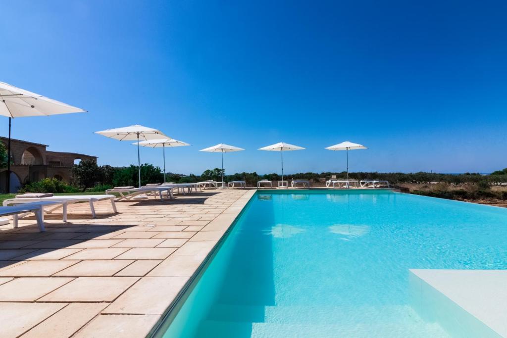 einen Pool mit Sonnenschirmen, Tischen und Stühlen in der Unterkunft Montiro' Hotel in Santa Maria di Leuca