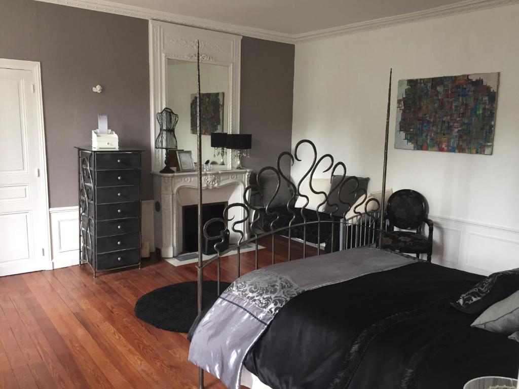 - une chambre avec un lit, une commode et une cheminée dans l'établissement Chateau Anaselle, à Condé-sur-Noireau