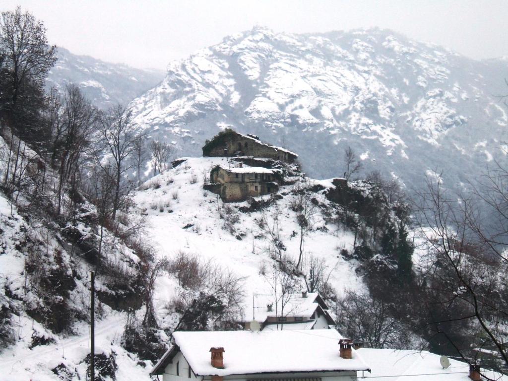 una montaña cubierta de nieve con una casa en el primer plano en Il Borgo en Sanfront