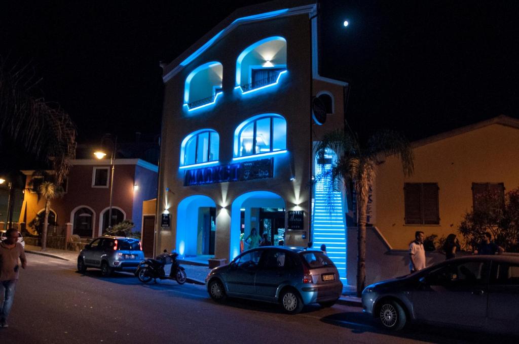 un edificio blu con macchine parcheggiate di fronte di Hotel Maria a Golfo Aranci