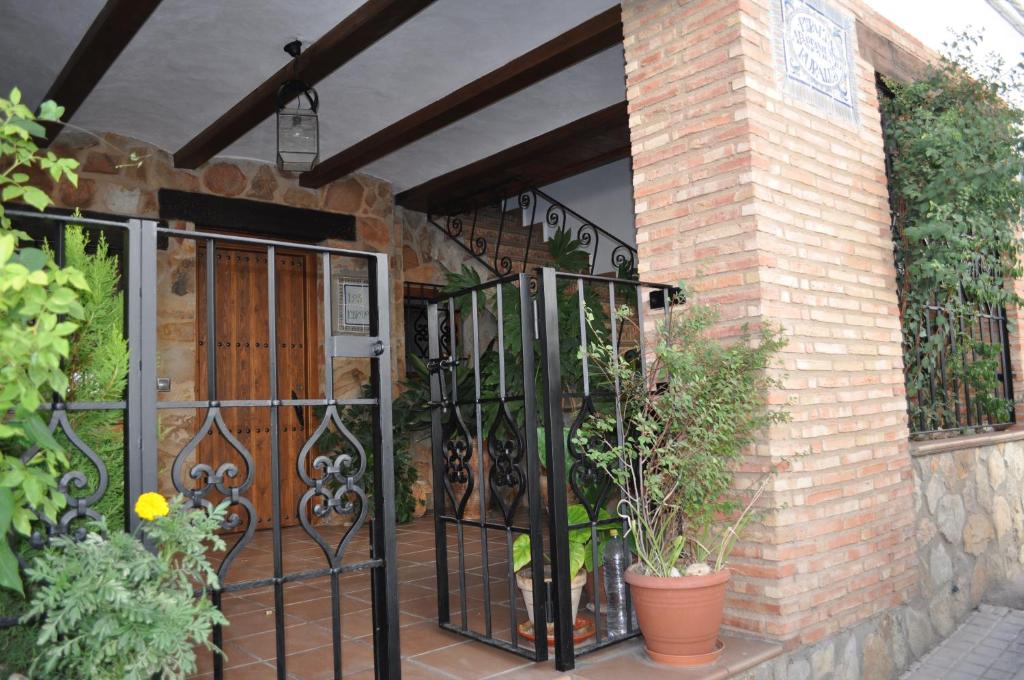 un portail en fer sur un bâtiment en briques avec des plantes dans l'établissement Apartamentos Rurales Peralta, à Segura de la Sierra