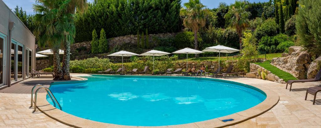 uma grande piscina azul com cadeiras e guarda-sis em Pural - Wool Valley Hotel & SPA na Covilh