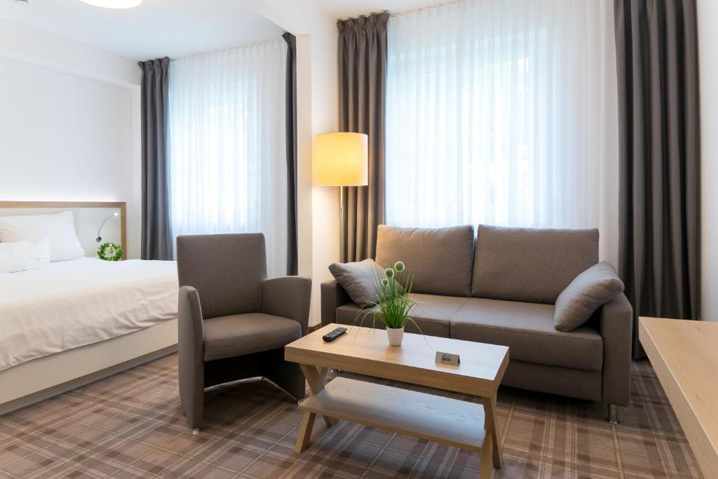 a hotel room with a bed and a couch and a table at Hotel zum Kuhhirten in Bremen
