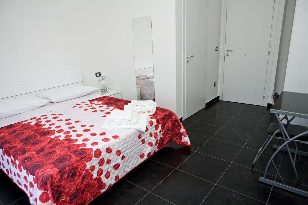 a bedroom with a bed with a red and white comforter at B&B Etna's Tourist in Catania
