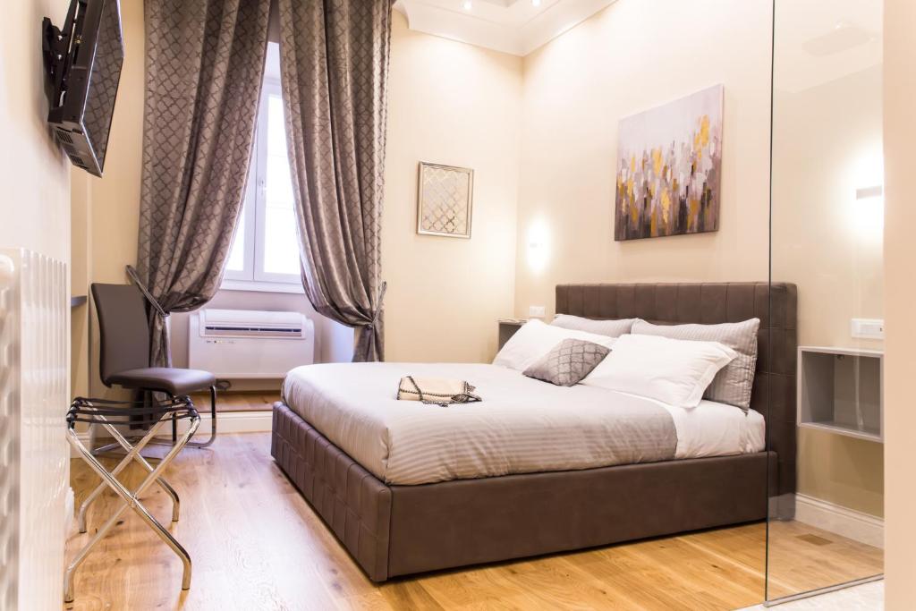 a bedroom with a bed and a chair and a window at Nazionale Palace Suites in Rome