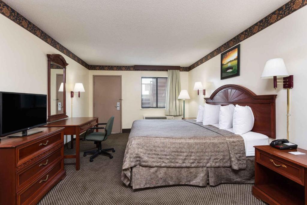 a hotel room with a bed and a desk and a television at Heritage Inn Augusta in Augusta