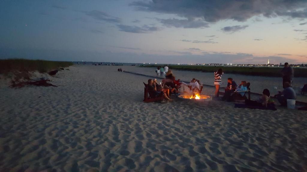 a group of people sitting around a bonfire on the beach at Blue Sea Motor Inn in North Truro