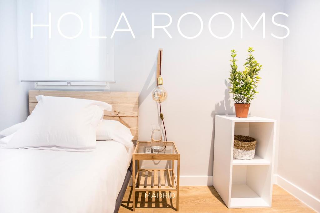 1 dormitorio con cama y mesita de noche con planta en Hola Rooms en Madrid