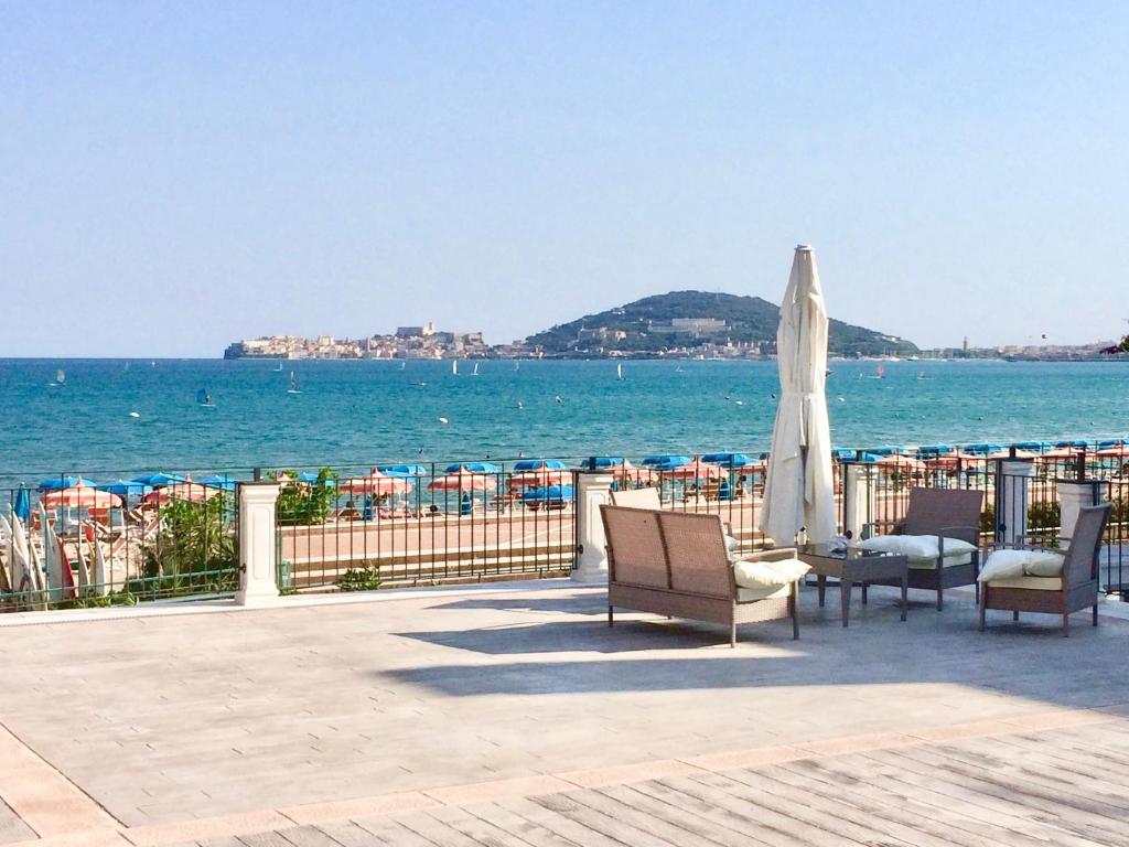 een patio met stoelen en een parasol en de oceaan bij Klaton Beach Hotel in Formia