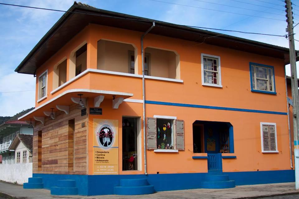um edifício laranja com janelas numa rua em Hostel Armazém do Heyokah em Urubici