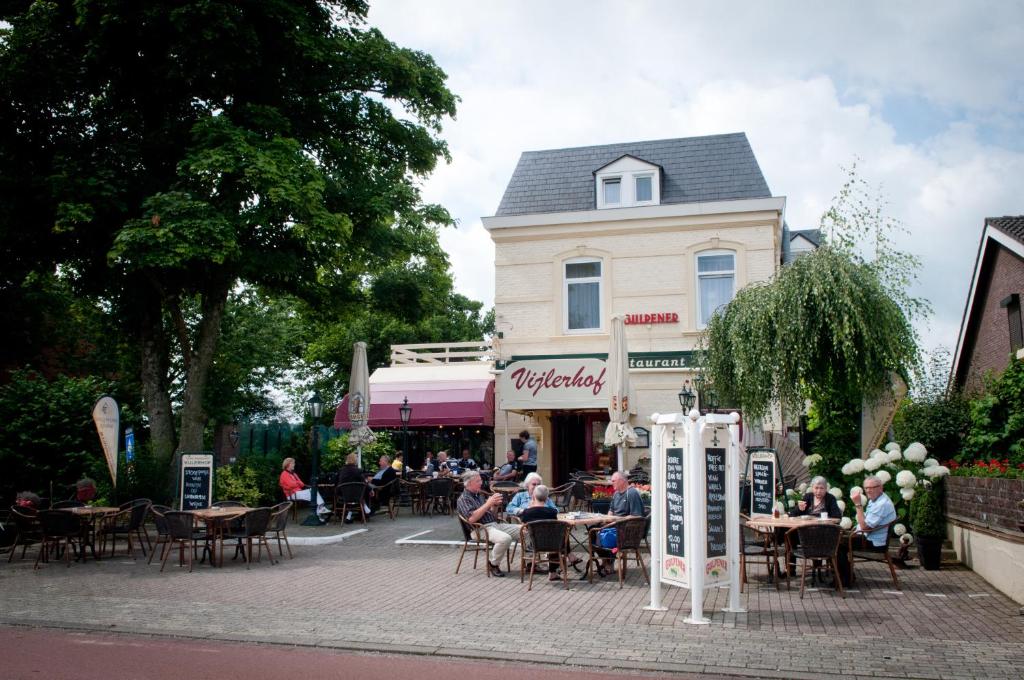 een groep mensen die aan tafels voor een gebouw zitten bij Hotel Restaurant Vijlerhof in Vijlen