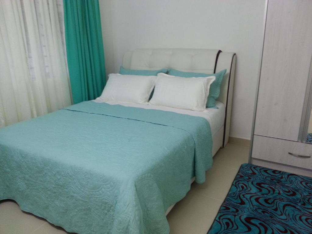 um quarto com uma cama com lençóis azuis e almofadas brancas em Homestay Farah Wangsa Maju KL em Kuala Lumpur