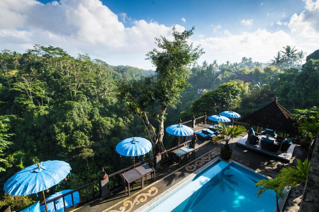 vista sulla piscina in un resort con ombrelloni di Villa Kalisat Resort ad Ubud