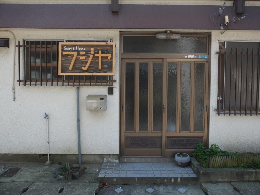 uma porta da frente de um edifício com um sinal nele em Fujiya em Matsuyama