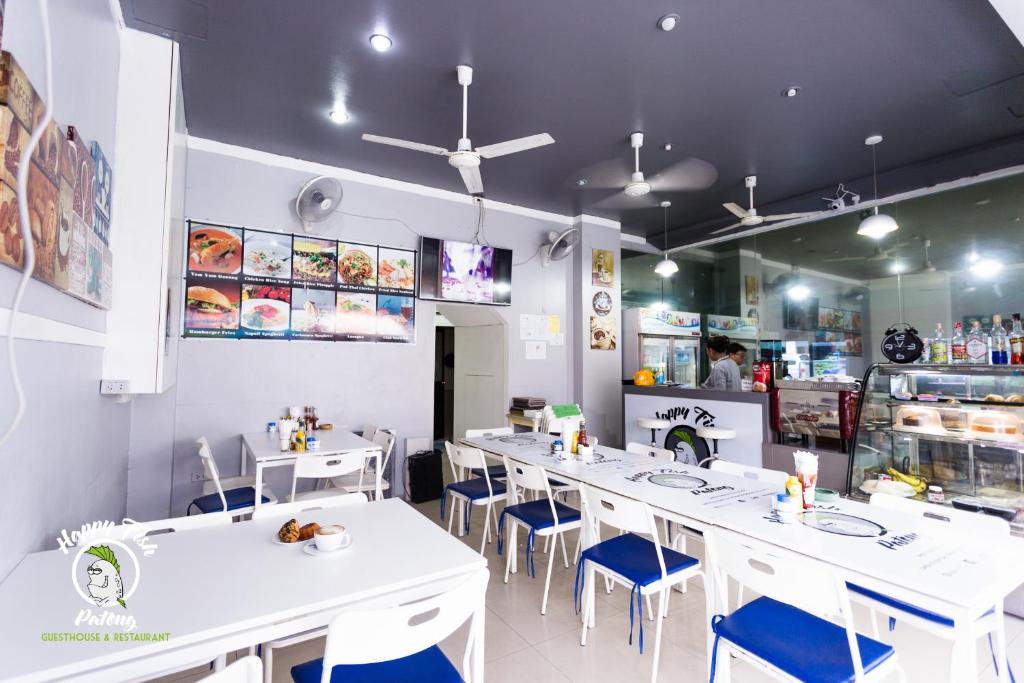 a restaurant with white tables and blue chairs at Happy Fish Guest House in Patong Beach