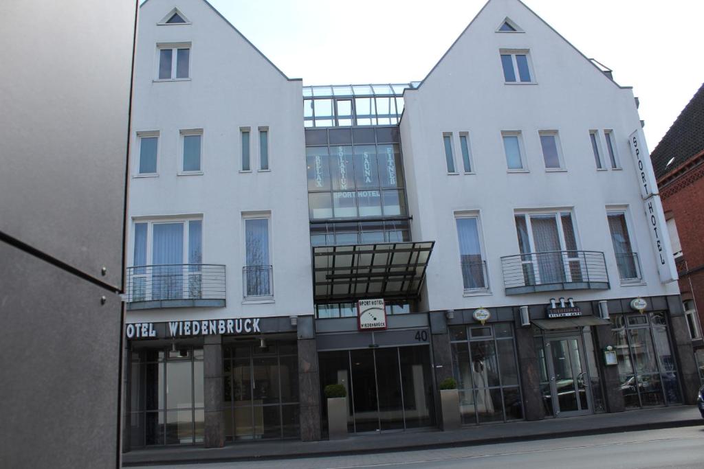 un grand bâtiment blanc avec une façade de magasin dans l'établissement Sporthotel Wiedenbrueck, à Rheda-Wiedenbrück