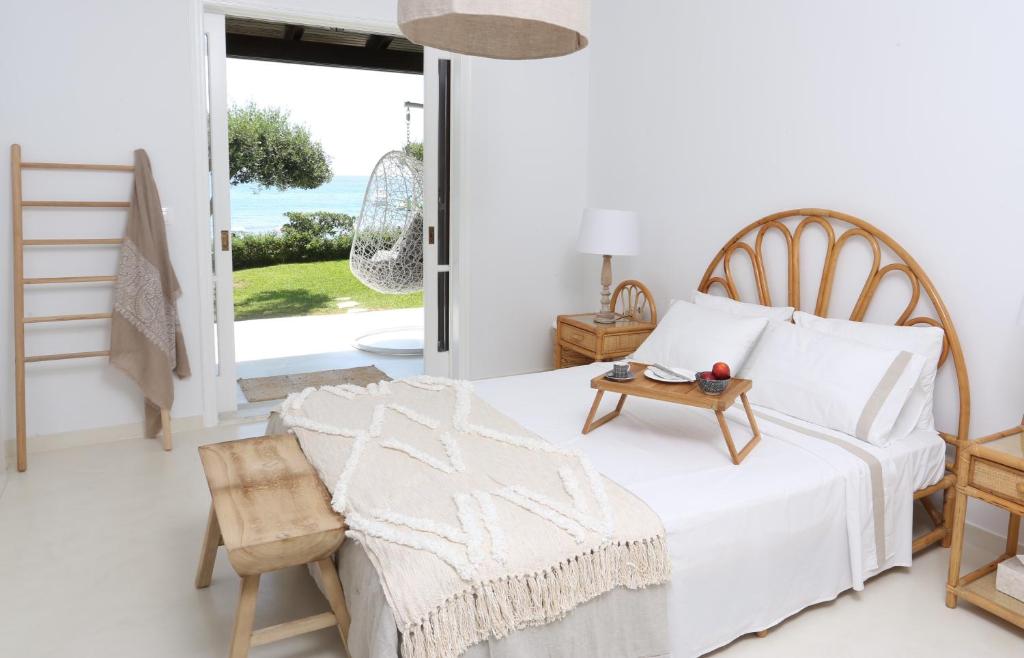 a white bedroom with a bed and a table at Seafront Calista Beach House With Garden in Glyfada