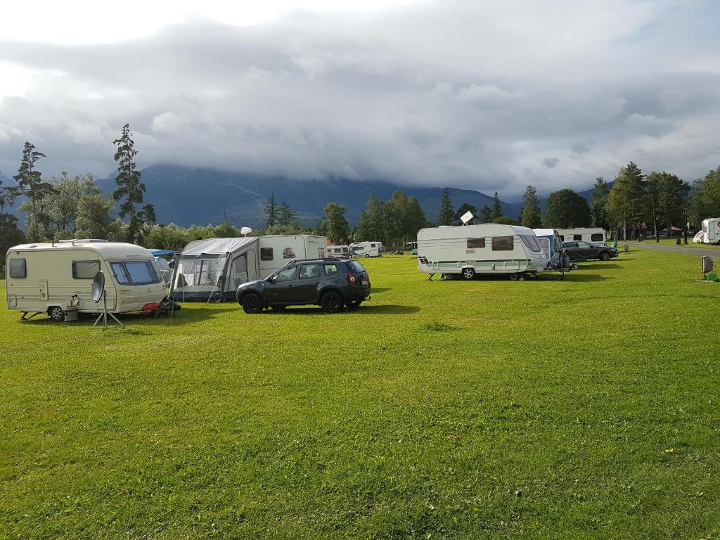 un grupo de tiendas de campaña y vehículos estacionados en un campo en Camping Intercamp Tatranec, en Tatranská Lomnica