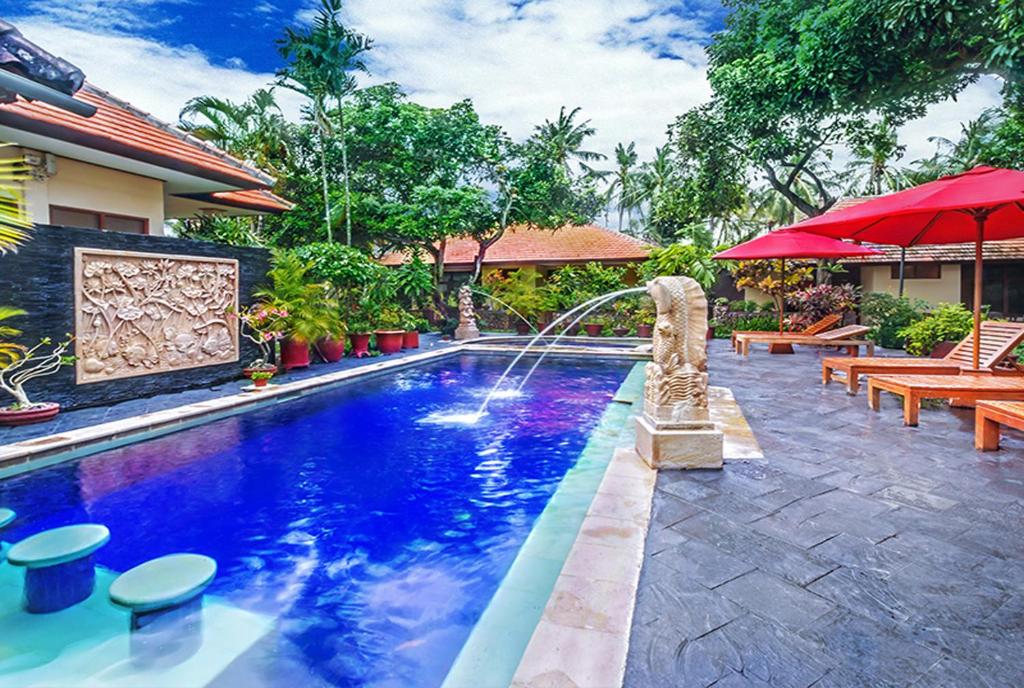 a swimming pool with a fountain in a resort at Yulia Beach Inn Kuta in Kuta