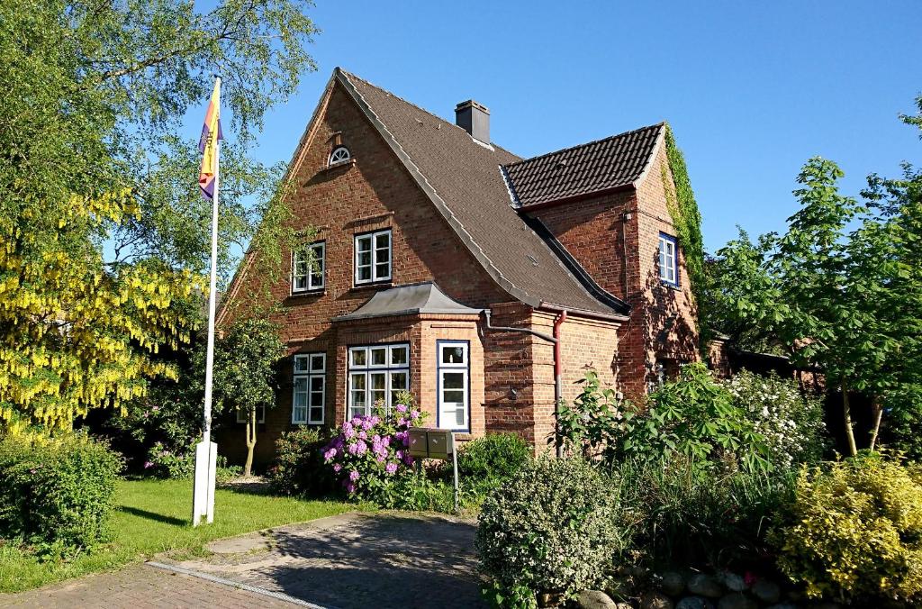 Alte Landjägerei Aukrug في Aukrug: منزل من الطوب مع العلم أمامه