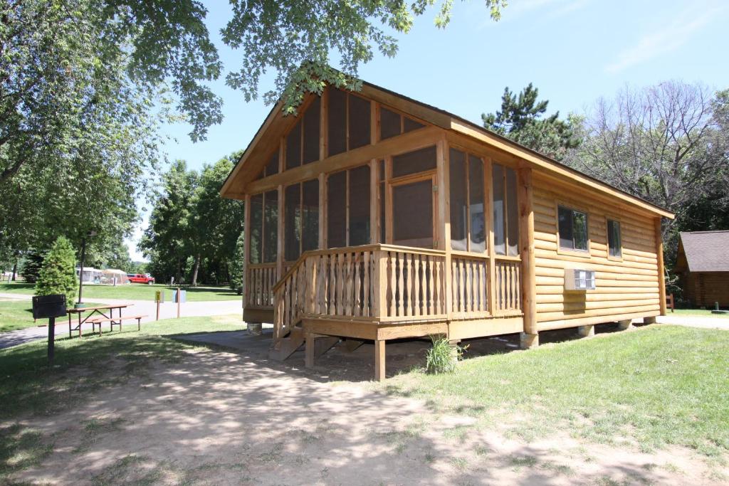 Cabaña de madera grande con mesa de picnic en un parque en Neshonoc Lakeside Camping Resort, en West Salem