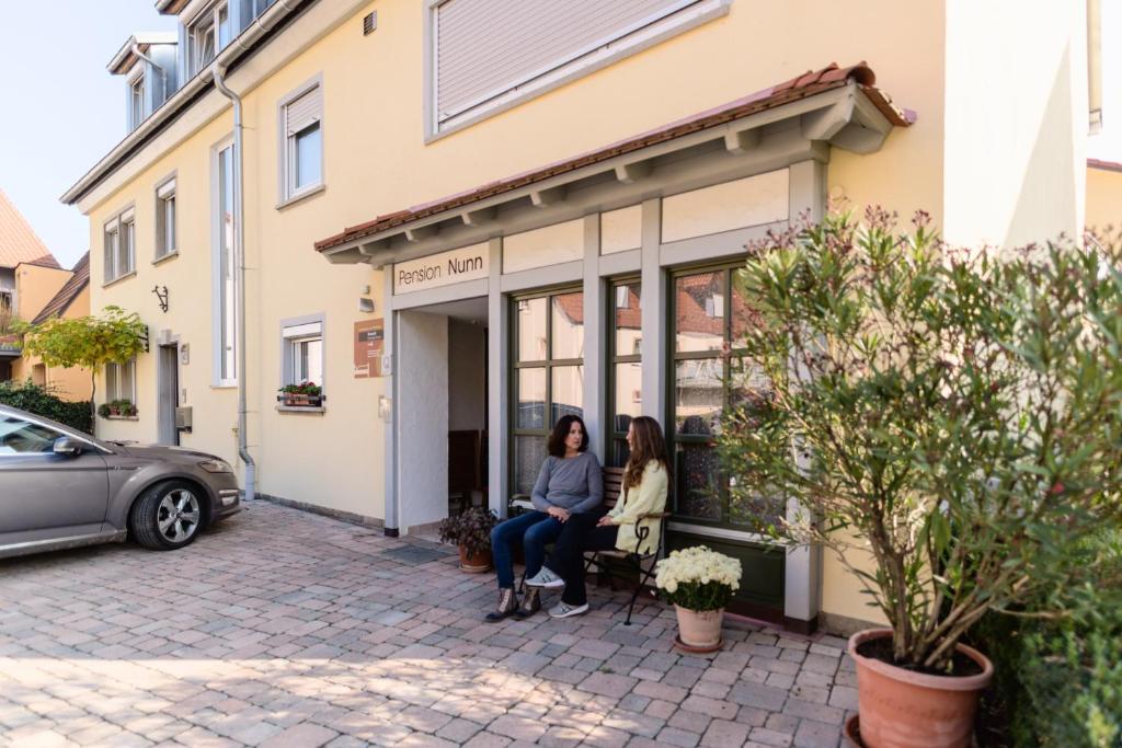 two women sitting on a bench outside of a building at Domizil Nunn in Escherndorf