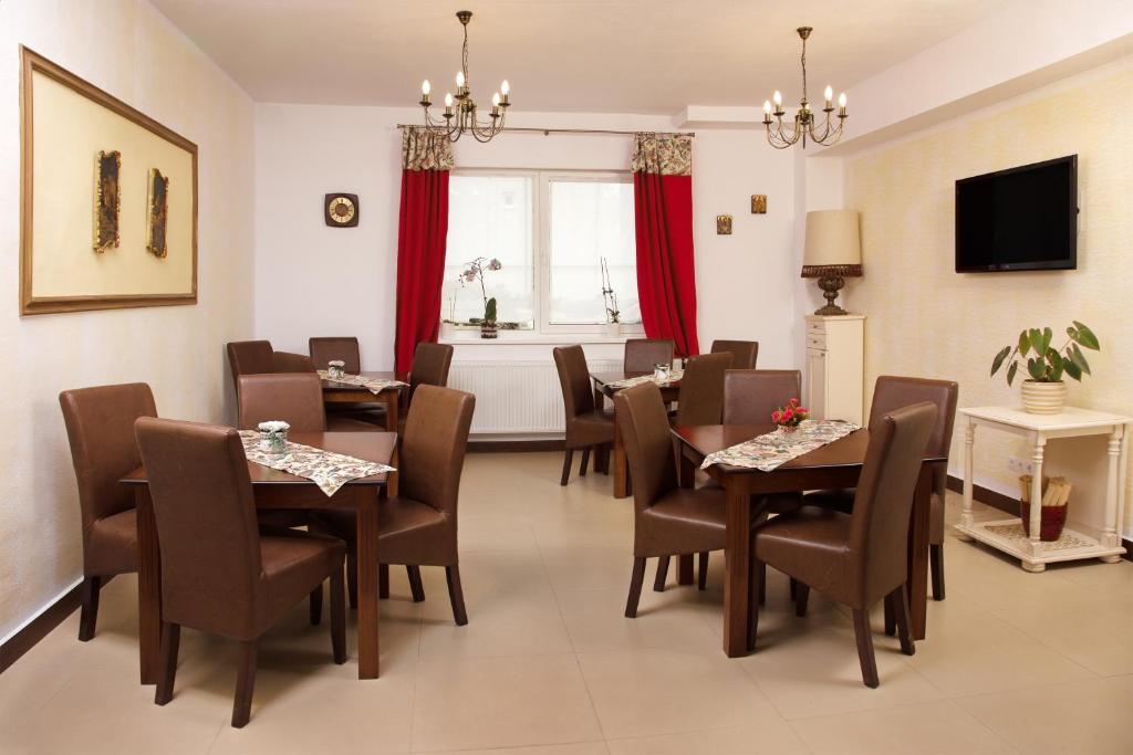 a dining room with tables and chairs and a television at Pensiunea Karola in Păltiniş