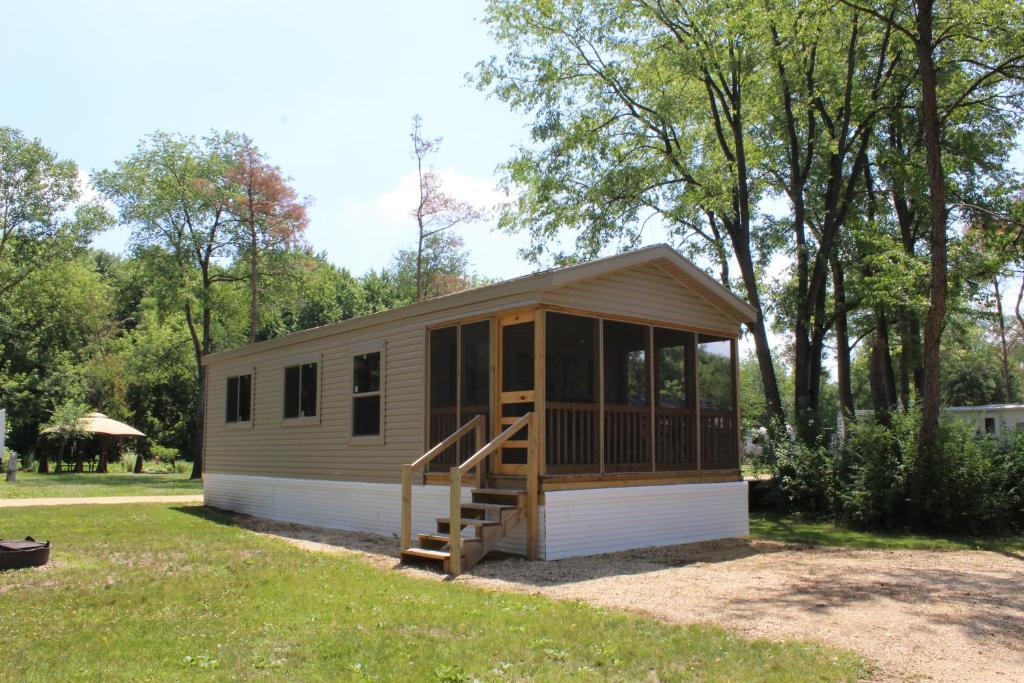 a tiny house with a porch and a staircase at Pine Country Camping Resort in Belvidere