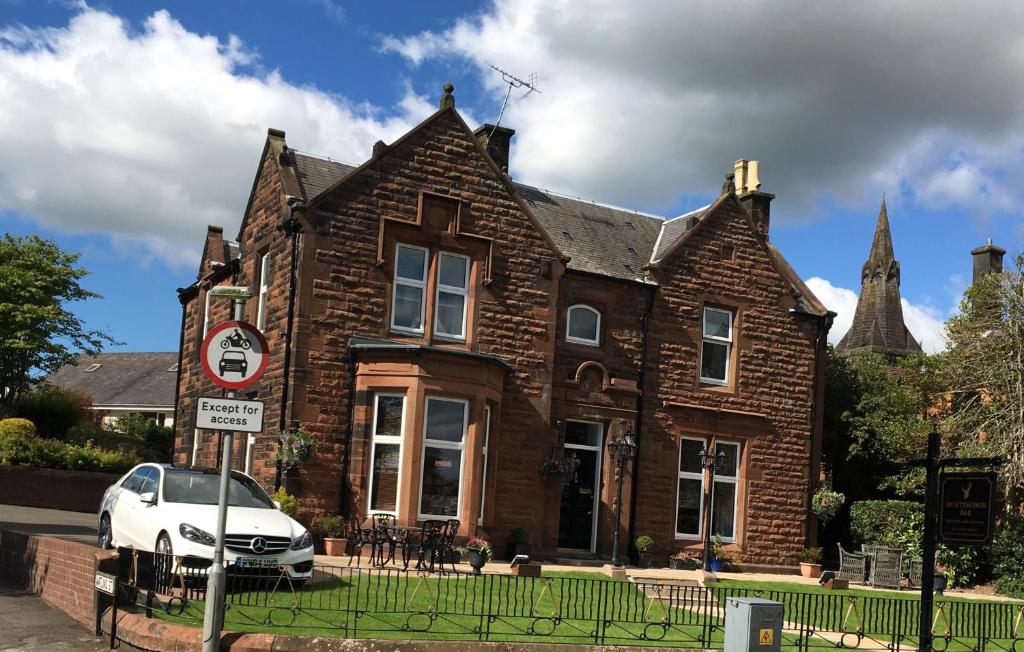 un coche blanco estacionado frente a un edificio de ladrillo en The Huntingdon, en Dumfries