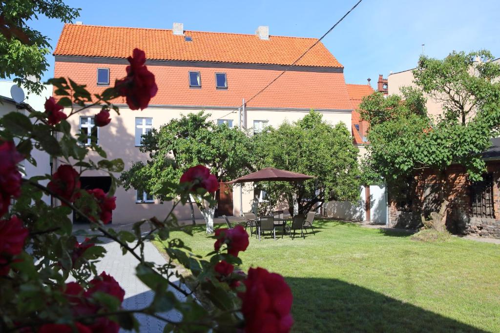 een gebouw met een tuin met rode bloemen op de voorgrond bij Apartamenty w sercu Chełmna in Chełmno