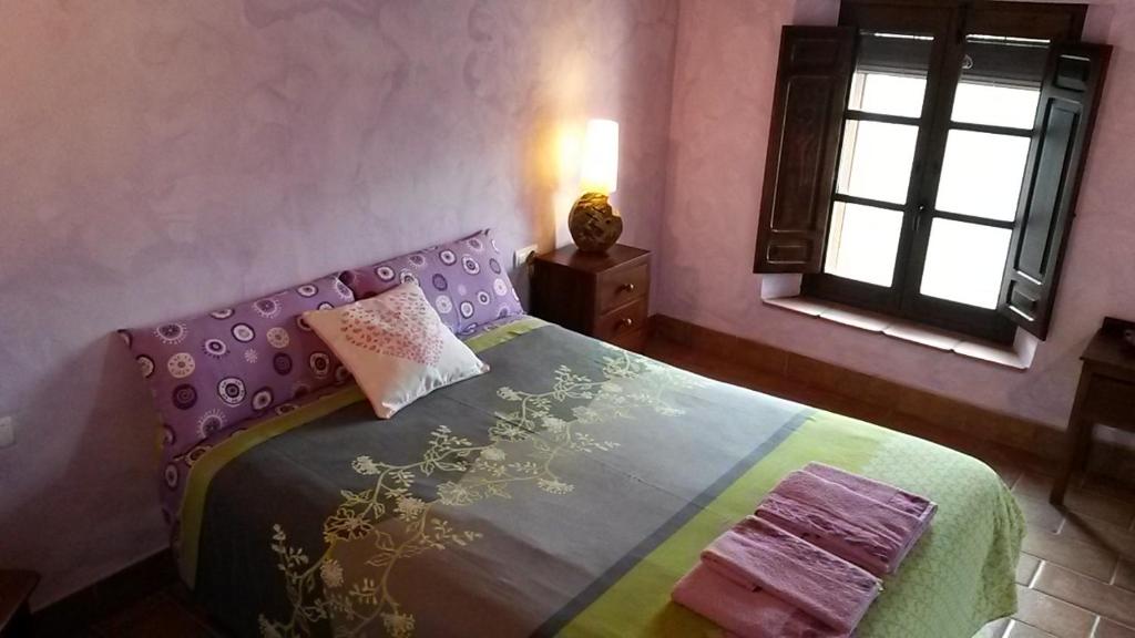 a bedroom with a bed with a colorful blanket and a window at Casa Rural del Rio in La Nava