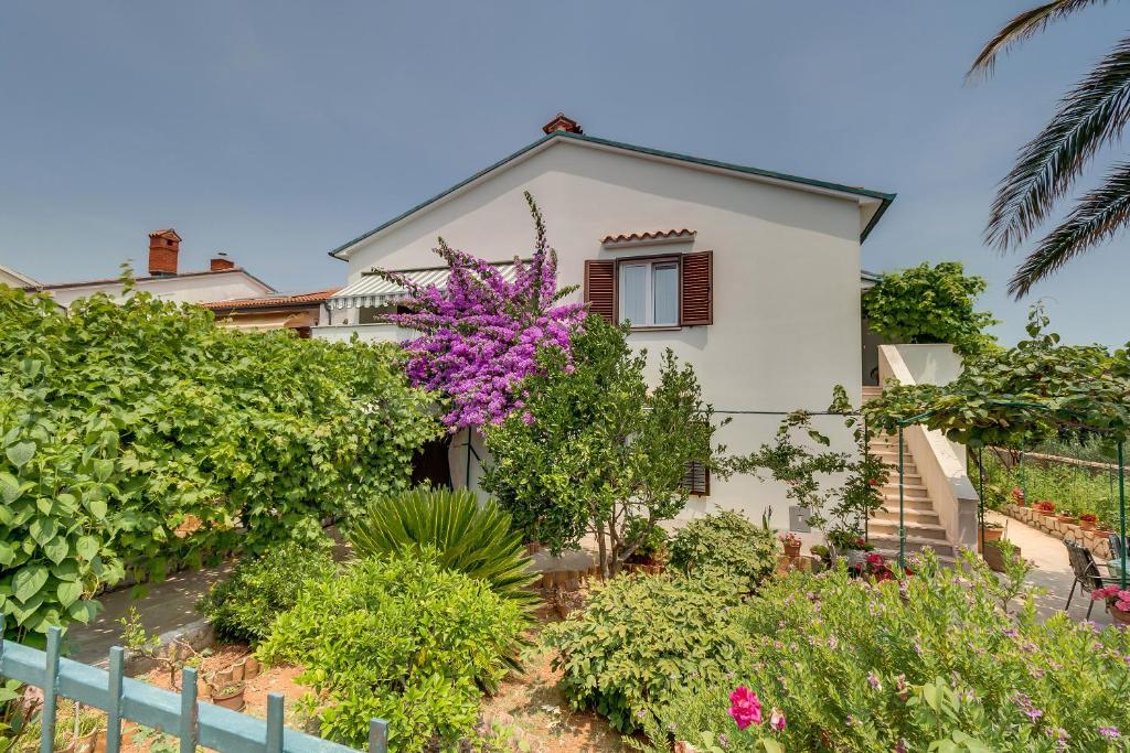 a house with flowering plants in front of it at Apartment Marisa in Mali Lošinj