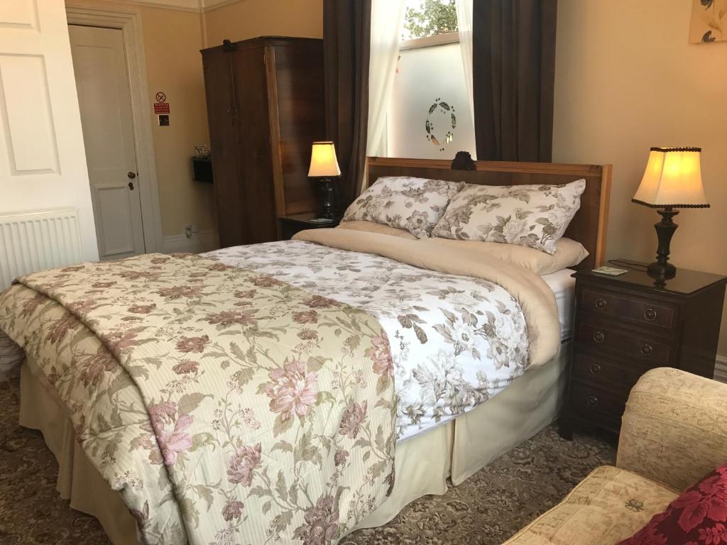 a bedroom with a bed and a dresser and lamp at The Hollies in Bridlington