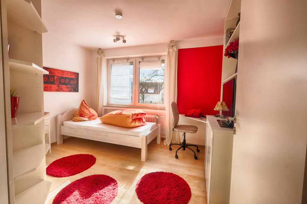 Kleines Zimmer mit einem Bett, einem Schreibtisch und roten Wänden. in der Unterkunft Pension Weinsberger Tal in Löwenstein