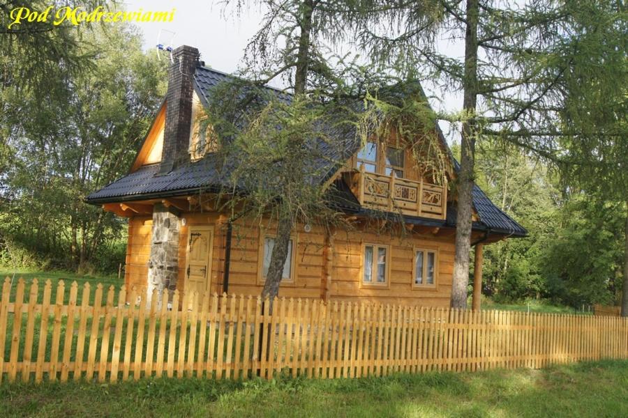 a log cabin with a fence in front of it at Pod Modrzewiami in Ciche