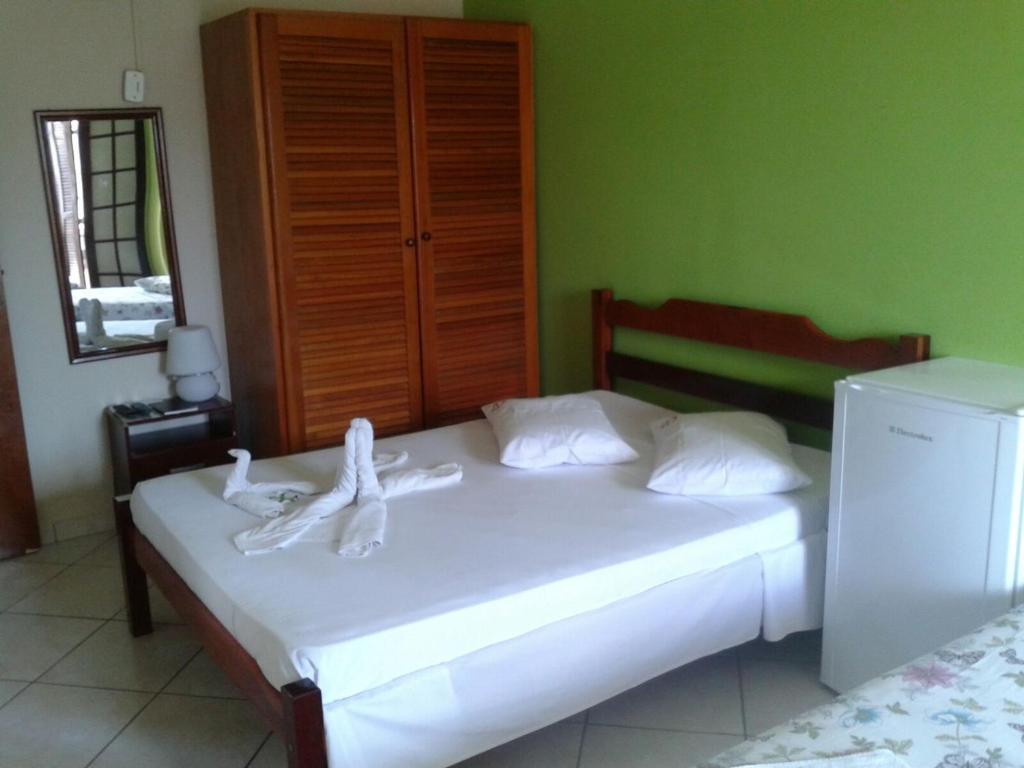 a bedroom with a white bed with towels on it at Pousada Alentejano II in Ubatuba
