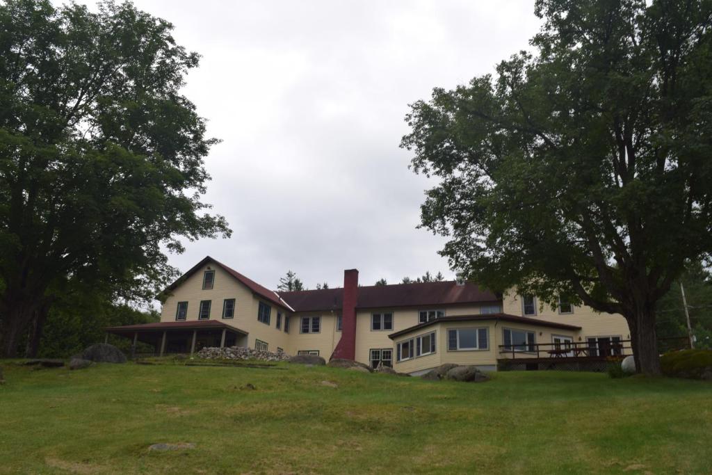 a large white house on a hill with trees at The Long View Lodge in Long Lake