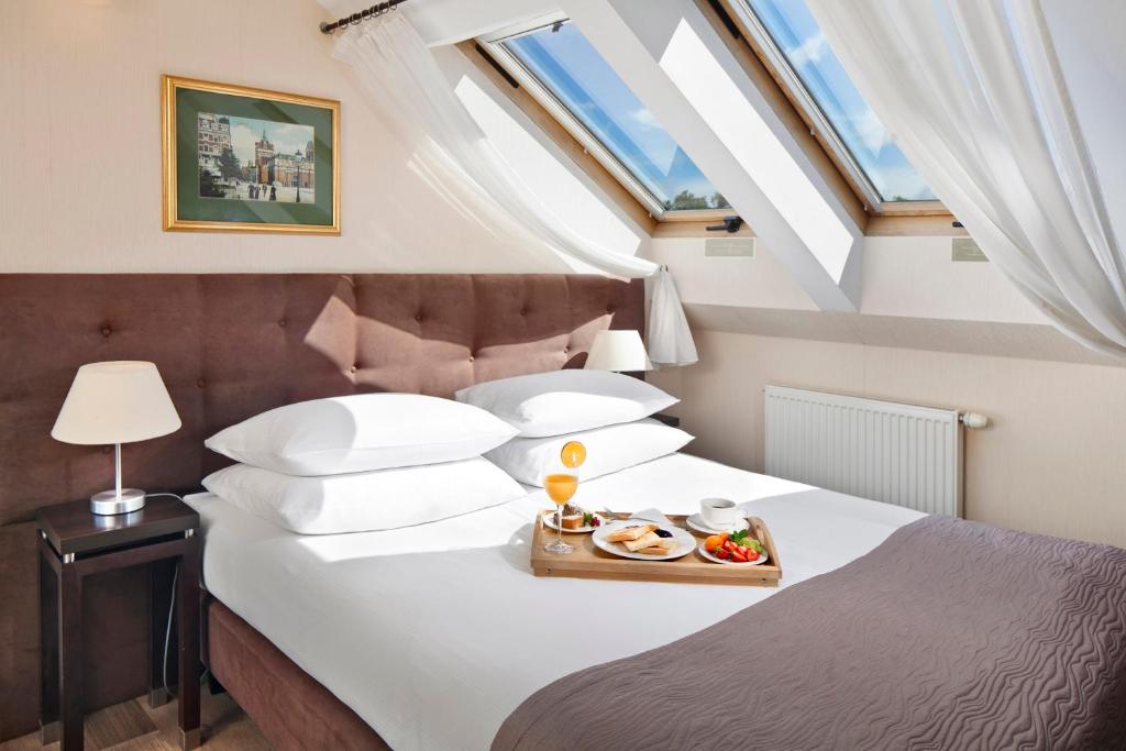 a bedroom with a bed with a tray of food on it at Hotel Bonum Old Town in Gdańsk